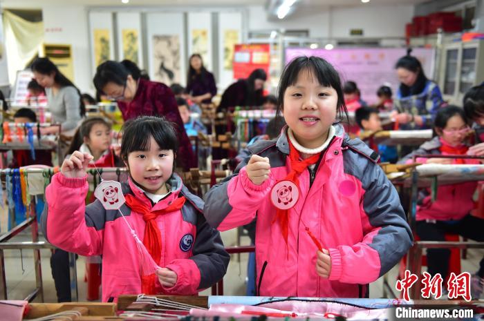 圖為小學生展示繡制好的2022年北京冬奧會吉祥物“冰墩墩”形象。　喻云亮 攝