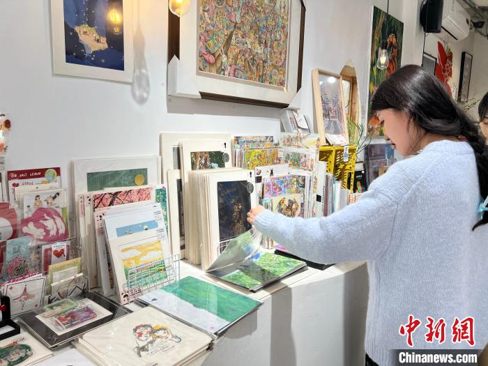 圖為藝術(shù)品商店內(nèi)，顧客挑選插畫作品?！＄婌?攝