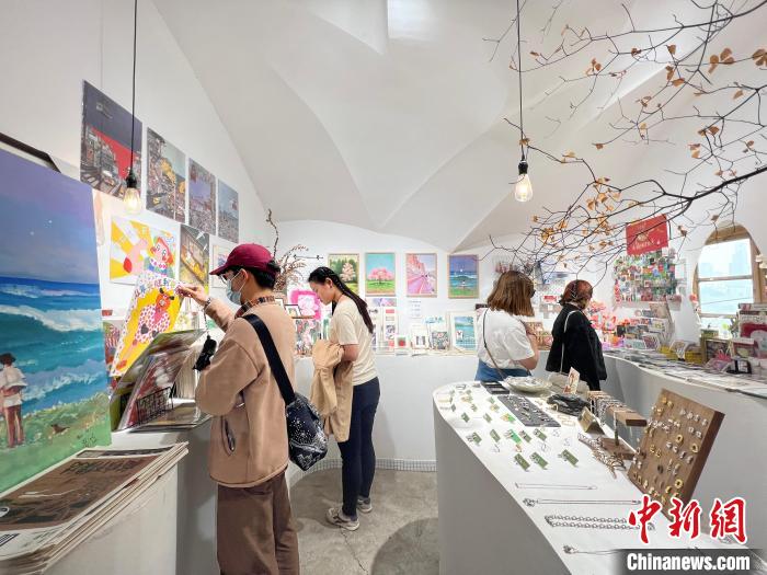 圖為藝術(shù)品商店內(nèi)，顧客挑選插畫作品?！＄婌?攝