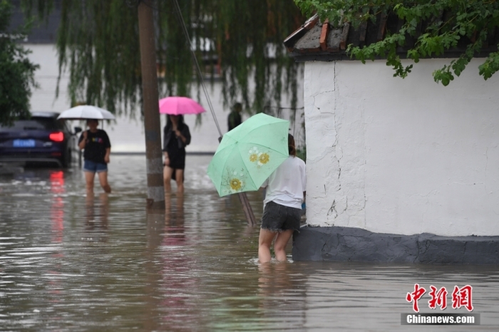 7月31日，市民行走在雨中的北京房山區(qū)瓦窯頭村。北京市氣象臺當(dāng)日10時發(fā)布分區(qū)域暴雨紅色預(yù)警信號。北京市水文總站發(fā)布洪水紅色預(yù)警，預(yù)計當(dāng)日12時至14時，房山區(qū)大石河流域?qū)⒊霈F(xiàn)紅色預(yù)警標(biāo)準(zhǔn)洪水。<a target='_blank' href='/'><p  align=