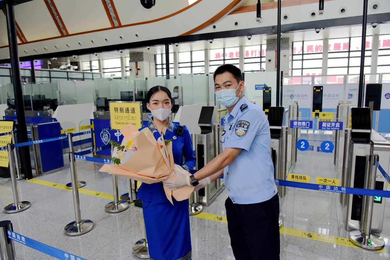 磨憨出入境邊防檢查站民警為中老鐵路第100萬名出入境旅客，D888次國際旅客列車老撾籍乘務員森達拉·妮緹婭（Sengdala Nitiya），送上鮮花。黃遠飛 攝