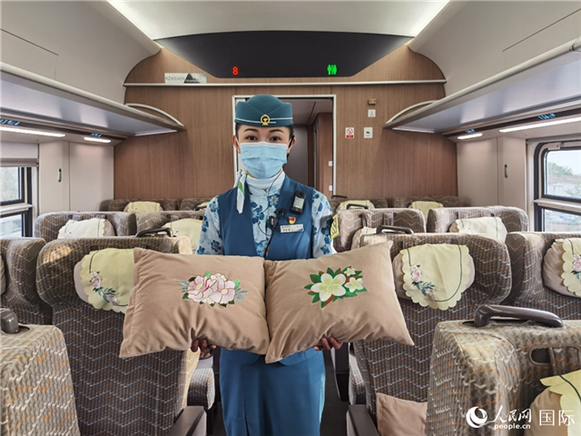趙瑩靜展示中老鐵路國際旅客列車?yán)飵в兄袊档せê屠蠐胝及突ù汤C圖案的靠墊。人民網(wǎng)記者 杜明明攝