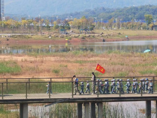 　　10月24日，秋游的幼兒園小朋友在老師帶領下走在清水塘公園里的木橋上。本報記者 常雯宜攝