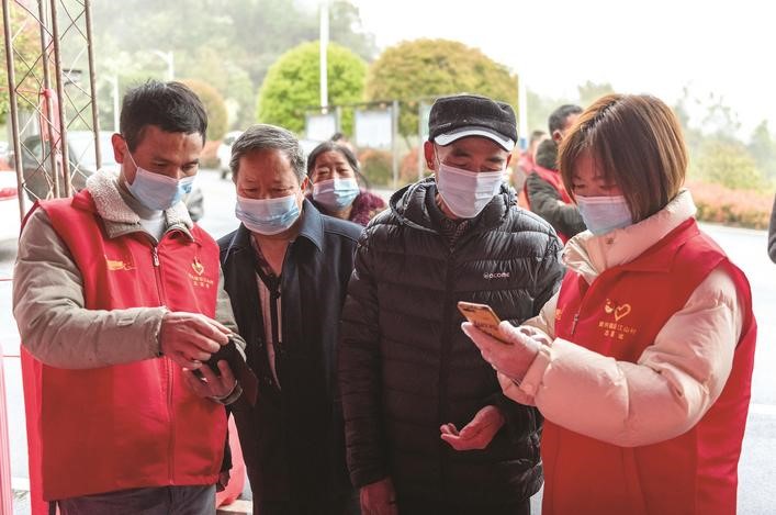 長(zhǎng)沙縣黨員志愿者正在幫助參與核酸檢測(cè)的群眾掃描“場(chǎng)所碼”。劉思源 攝