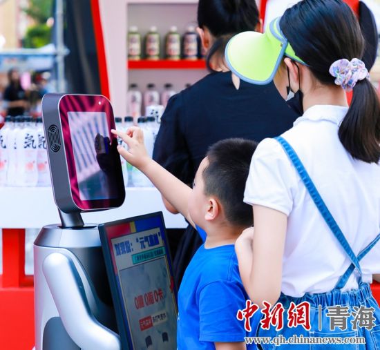 圖為一名小朋友正在和機器人“志愿者”進行互動。 沐聞 攝
