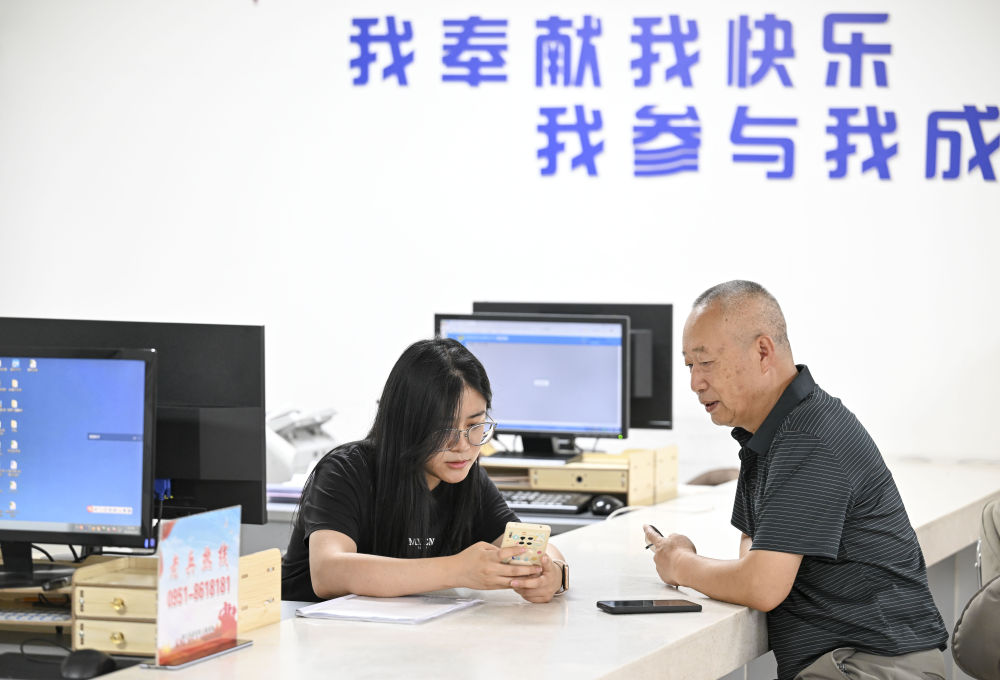 2024年6月20日，在寧夏銀川市金鳳區(qū)長(zhǎng)城花園社區(qū)黨群服務(wù)中心，工作人員幫助居民辦理業(yè)務(wù)。圖片來(lái)源 新華社