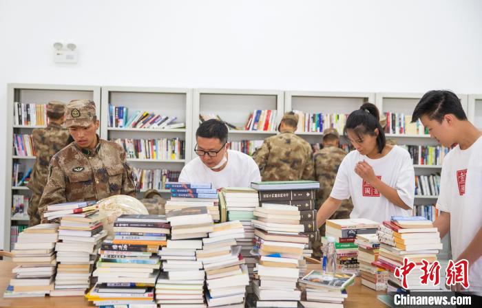 圖為志愿者們和邊防戰(zhàn)士整理圖書?！詵| 攝