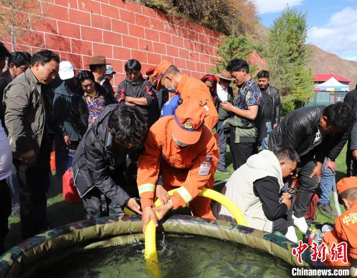 圖為森林消防員為護林員講解滅火裝備的使用方法?！〔际猩窒乐ш?供圖