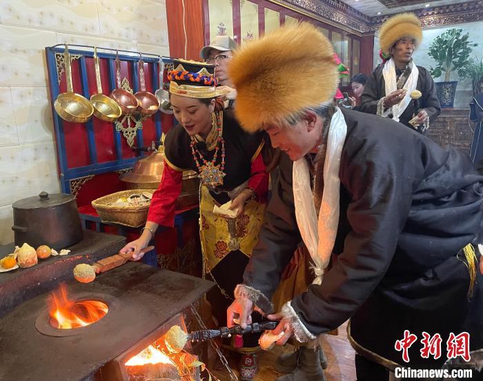 圖為人們在火上烤節(jié)日美食“結達”?！∪轿木?攝