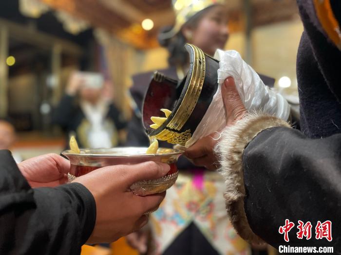 圖為主人在碗中斟滿青稞酒?！∪轿木?攝