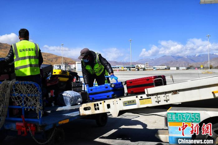 圖為機(jī)場工作人員傳送旅客行李箱?！≈芎?攝