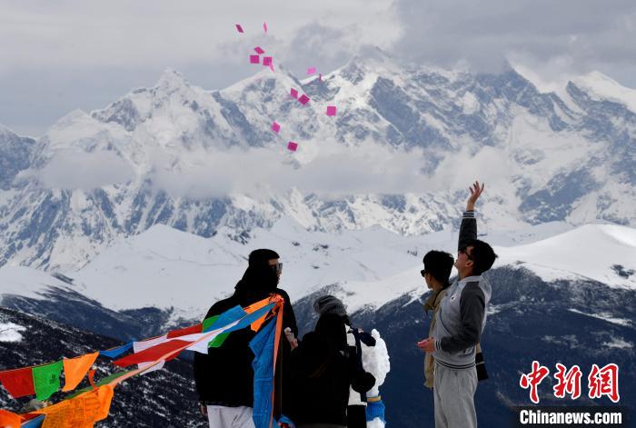 圖為5月14日，游客在西藏林芝色季拉山觀(guān)景臺(tái)拋灑“隆達(dá)”(風(fēng)馬旗，藏族民眾的一種祈福方式)?！±盍?攝