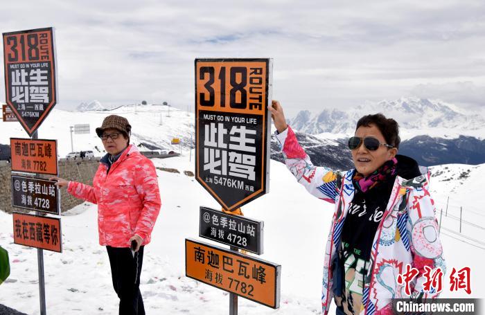 圖為5月14日，西藏林芝色季拉山觀(guān)景臺(tái)，游客與南迦巴瓦峰合影。　李林 攝